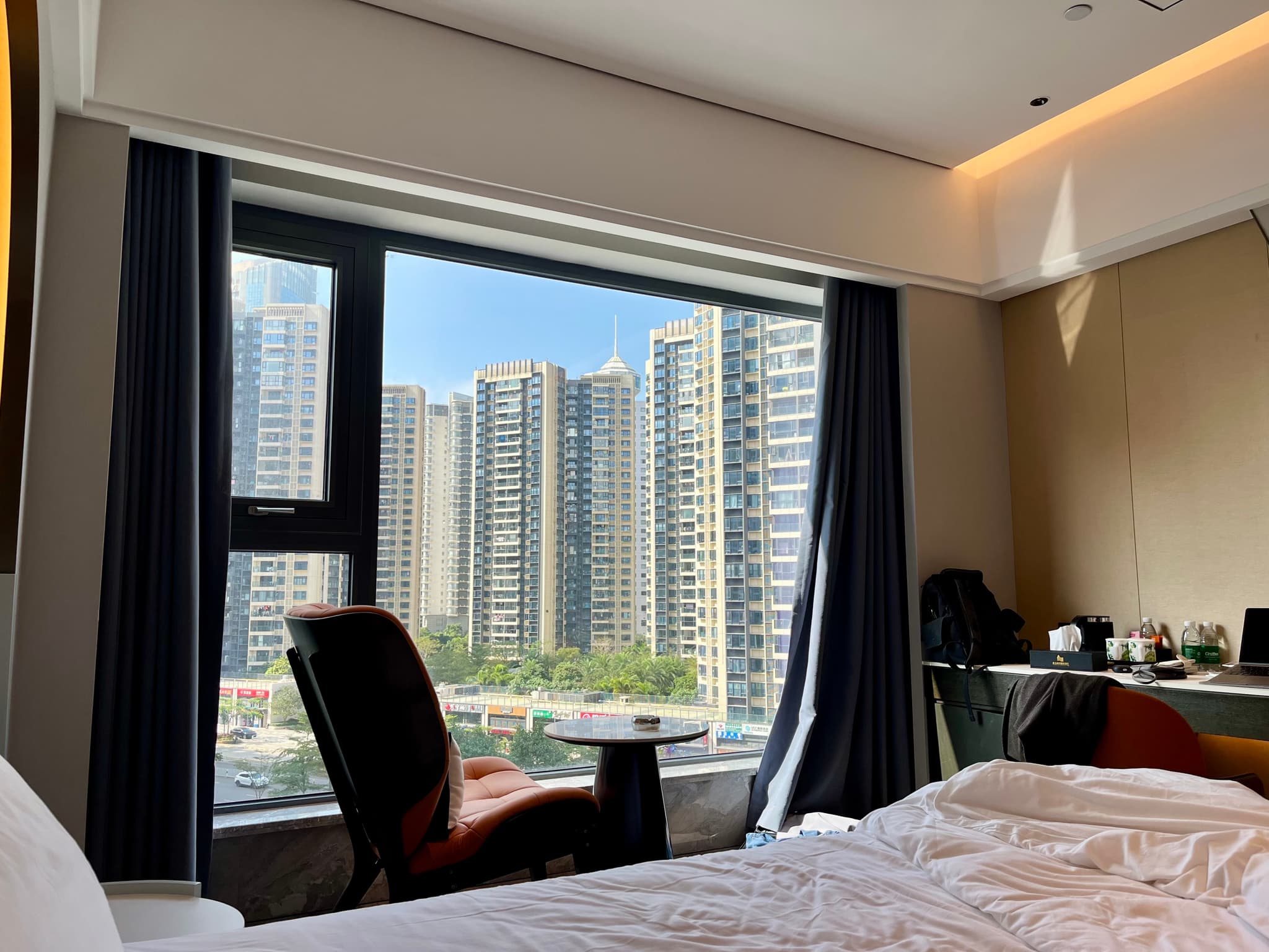 A view from a hotel room window overlooking a dense urban landscape of apartment buildings under a clear sky