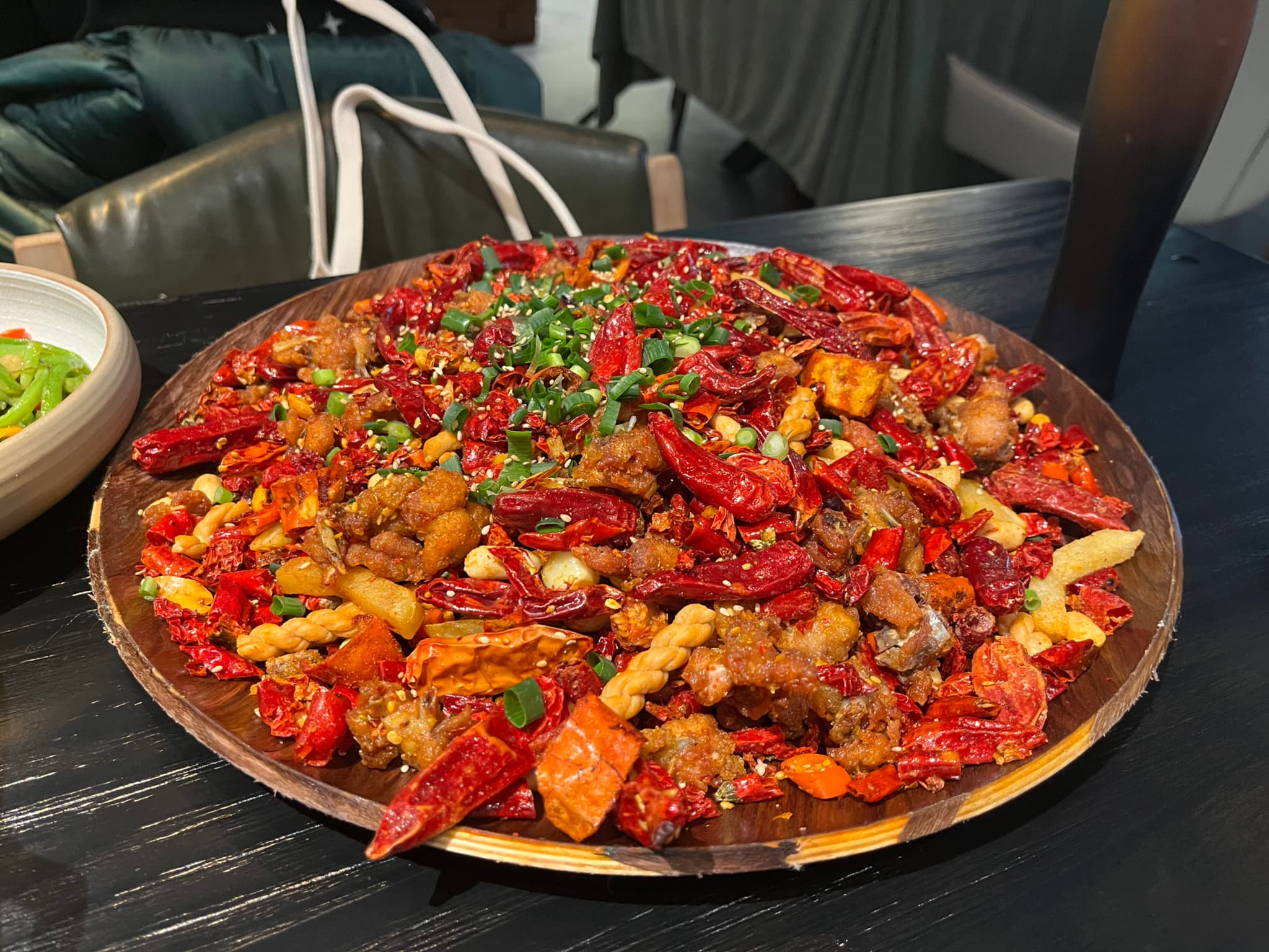 A large plate of spicy stir-fried crawfish garnished with chopped green onions