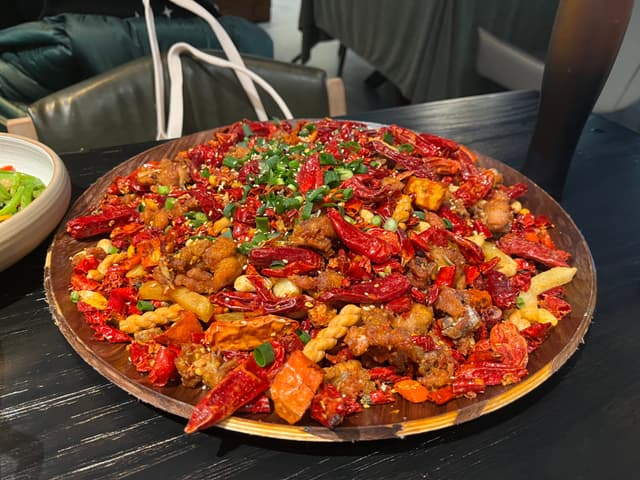 A large plate of spicy stir-fried crawfish garnished with chopped green onions