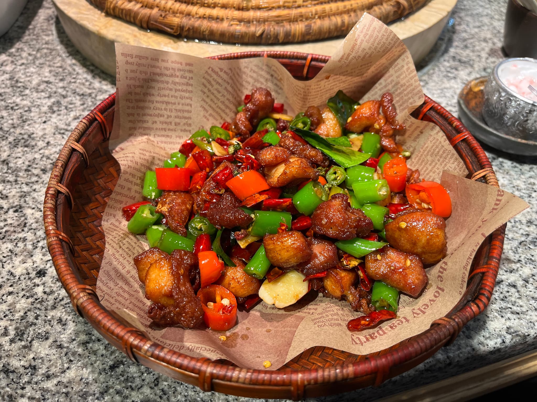 A close-up shot of a delicious bowl of spicy chicken with chili peppers and green peppers