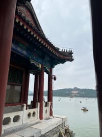 古典宫殿建筑在湖边，湖中有船只，远处有山丘建筑。