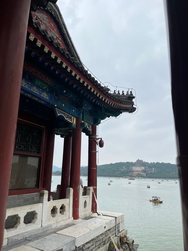 古典宫殿建筑在湖边，湖中有船只，远处有山丘建筑。