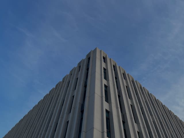 A corner view of a tall, rectangular building with vertical lines against a clear blue sky