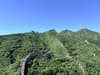 Winding stone wall crossing forested mountain ridges beneath a clear blue sky