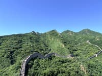 Winding stone wall crossing forested mountain ridges beneath a clear blue sky