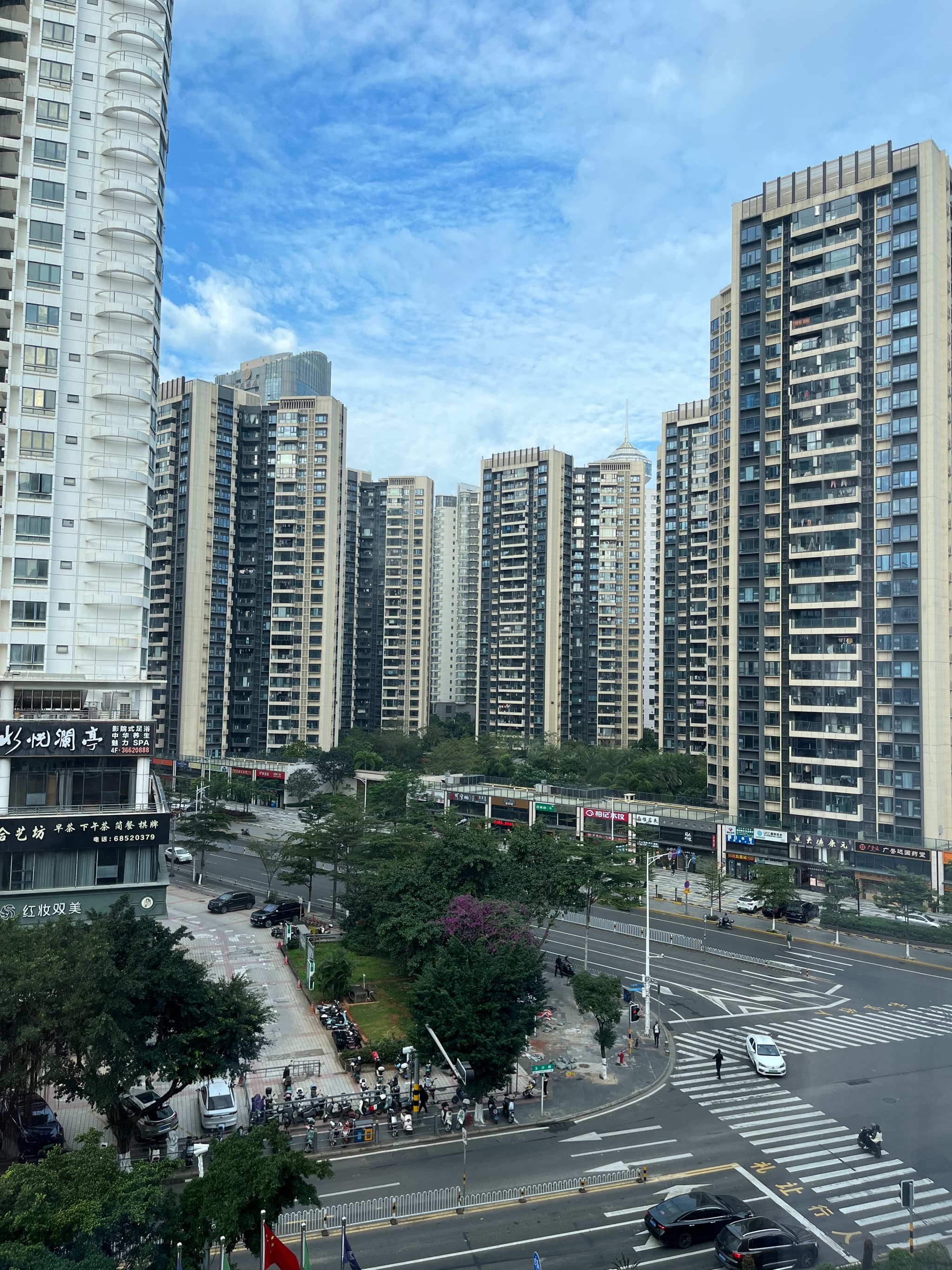 A wide view of a densely populated urban area with numerous tall apartment buildings under a partly cloudy blue sky