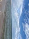 Cloud-dappled sky above a textured shoreline and open water
