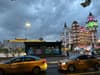 A vibrant urban scene featuring yellow taxis, colorful buildings, and a cloudy sky, flipped upside down
