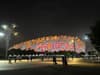 Illuminated stadium at night with a complex, bird's nest-like exterior structure