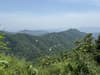 Layered forested mountain ridges beneath a hazy blue horizon
