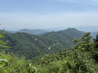 Layered forested mountain ridges beneath a hazy blue horizon
