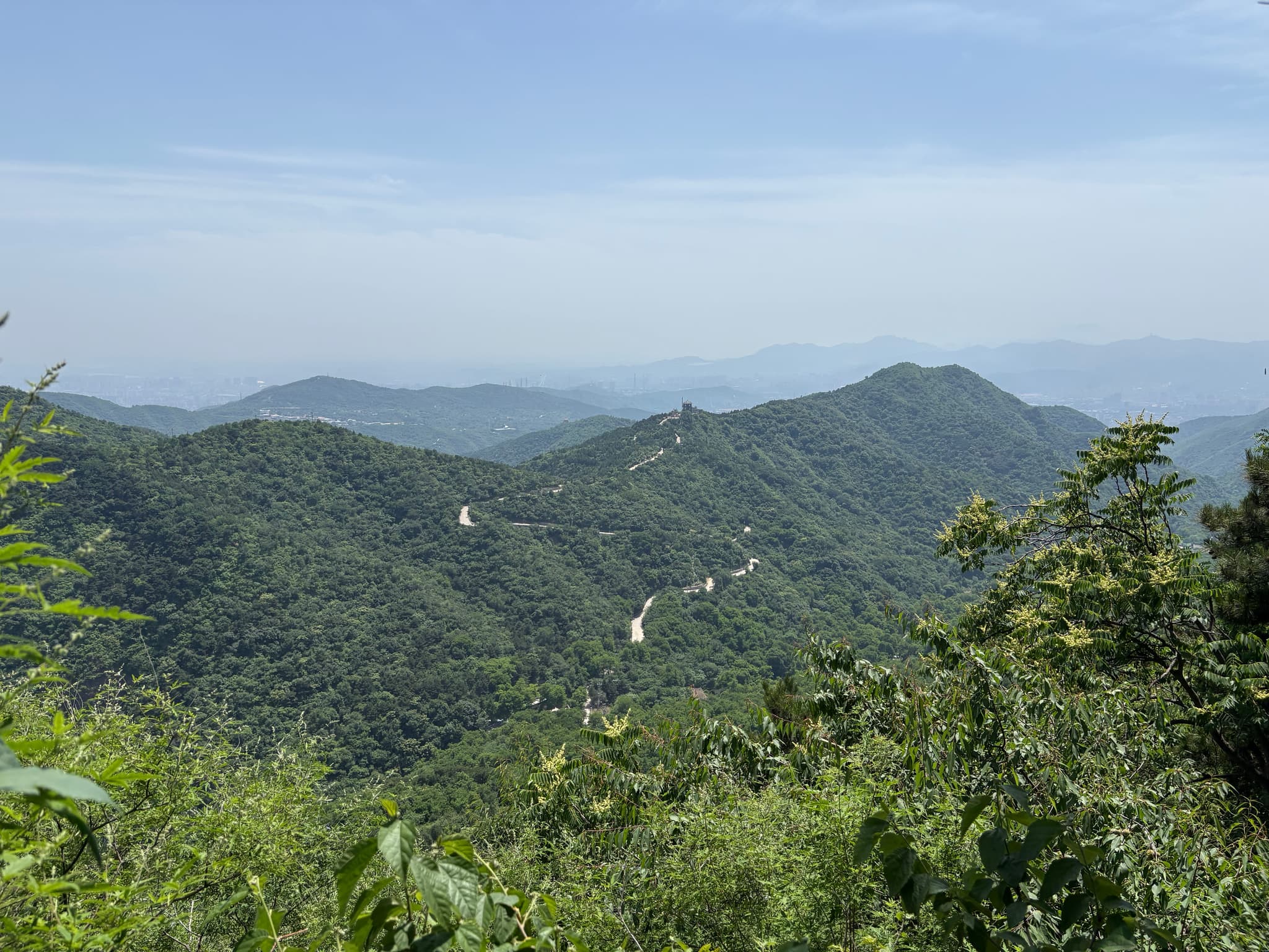 Layered forested mountain ridges beneath a hazy blue horizon