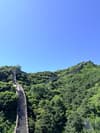 Stone ramparts winding through forested mountain ridges beneath a blue sky