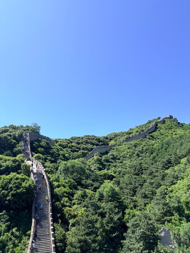 Stone ramparts winding through forested mountain ridges beneath a blue sky