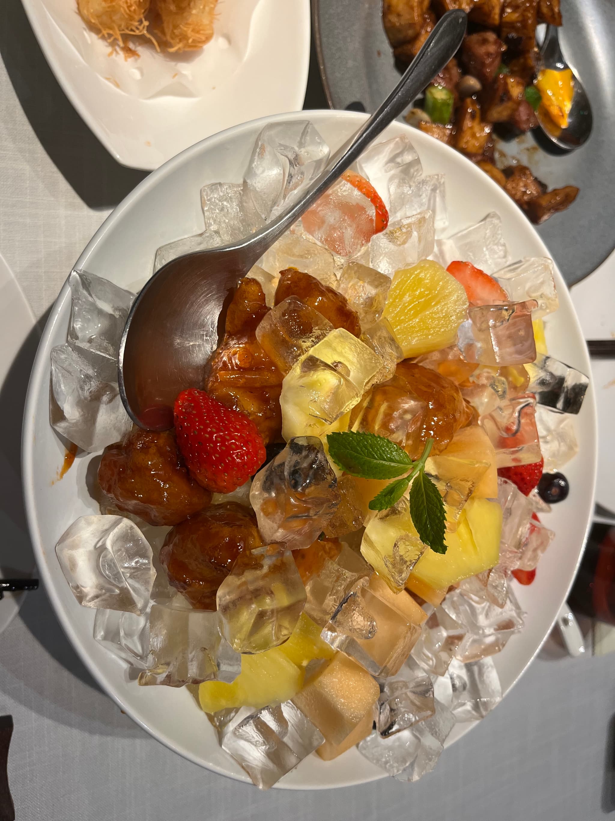 冰镇水果拼盘，包含草莓、菠萝、橘子等水果，装饰有薄荷叶。