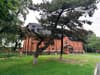 Red brick hall surrounded by pine trees and lawn
